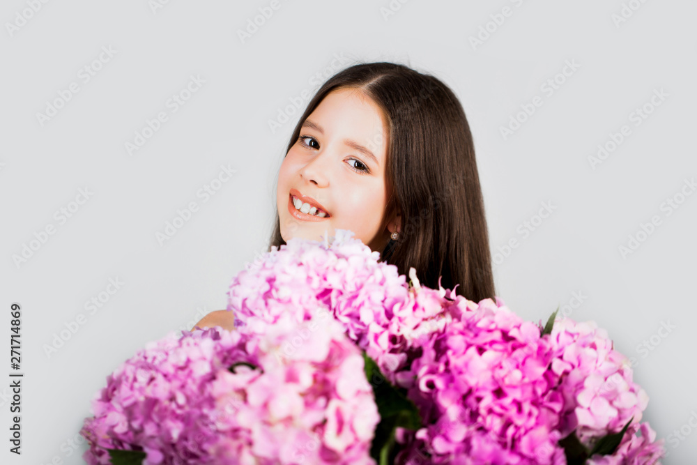 Sweet toddler girl with floral on and flowers bunch in hands. Child. Childhood. Kids. Portrait of a smiling little girl holding flowers. Cute little girl on the in spring day