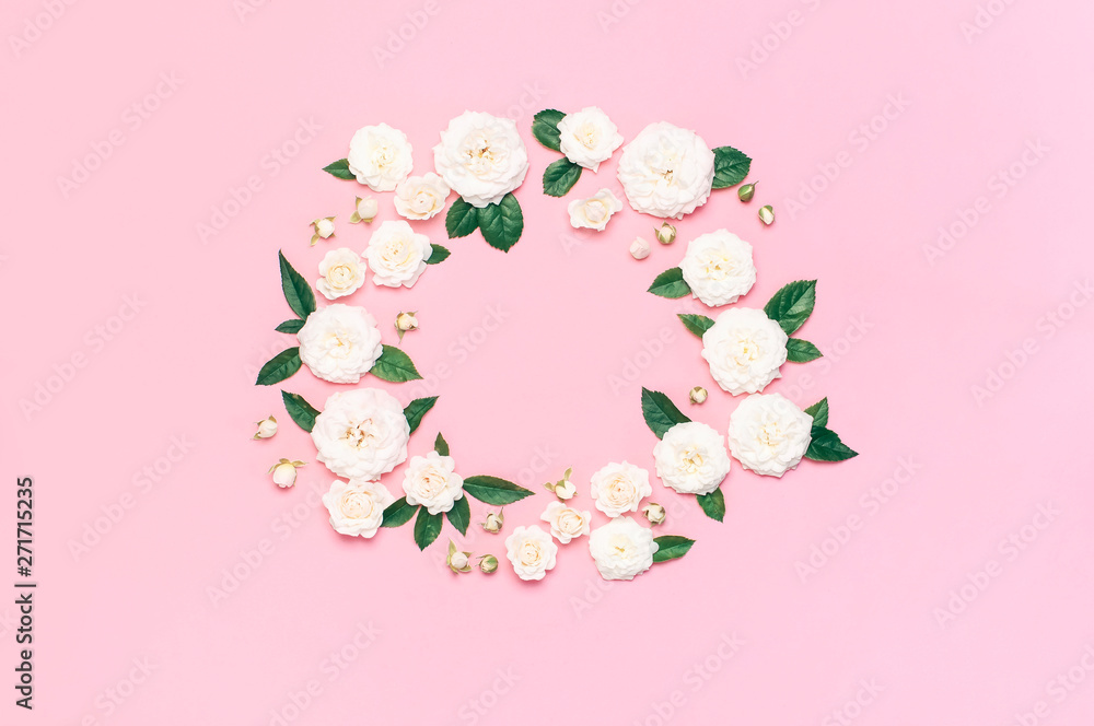 Flowers composition. Frame in the form of circle of white fresh roses and green leaves on gentle pink background. Flat lay, top view, copy space. Flower card, greeting, holiday mockup, womens day