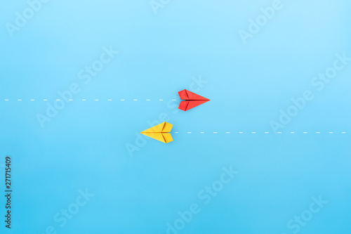 Red and yellow paper planes flying in different directions, blue background. dissenting opinion, divergent views concepts photo