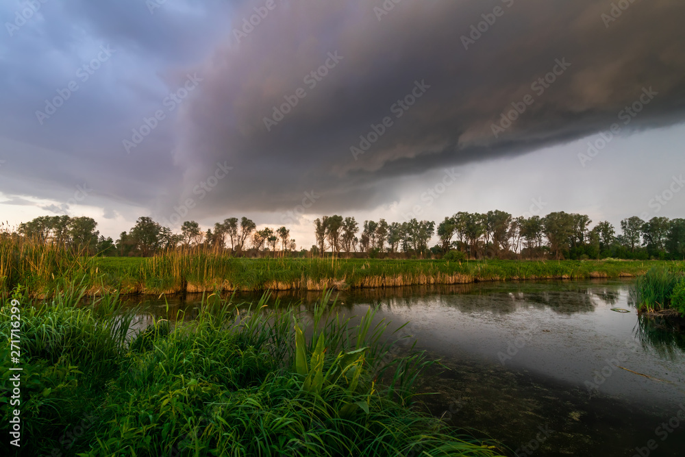 Thundercloud over the river. Summer landscape before the storm.