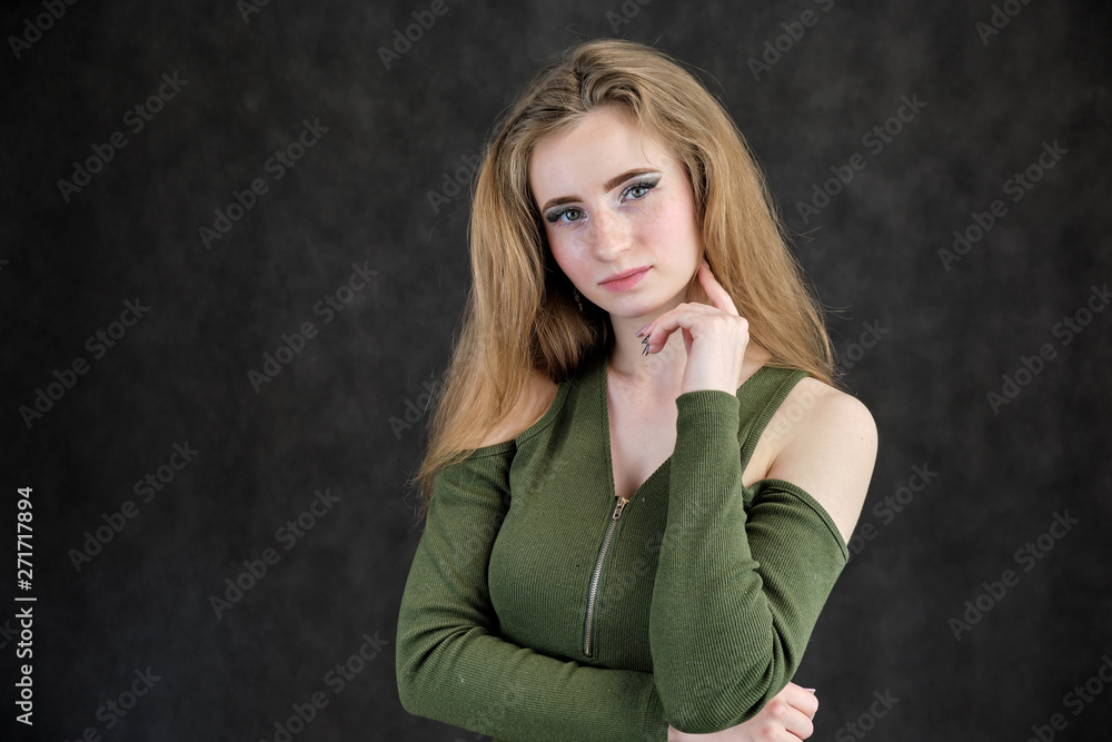 Photo portrait of a beautiful girl woman on a dark gray background with long flowing beautiful hair in a green dress standing right in front of the camera and smiling. Photo portrait of a beautiful girl woman on a dark gray background with long flowing beautiful hair in a green dress standing right in front of the camera and smiling.