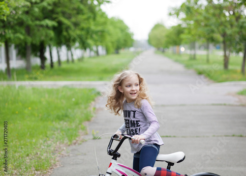 Beautiful blonde young girl riding a white bicycle © supersomik