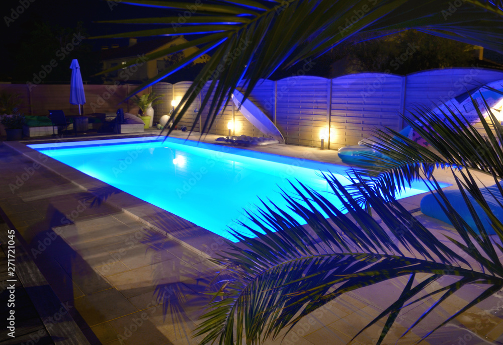 water of swimming pool illuminated in blue by night - obrazy, fototapety, plakaty 