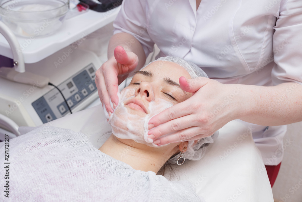 Applying foam to the face of the girl before the mesotherapy procedure Applying foam to the face of the girl before the mesotherapy procedure