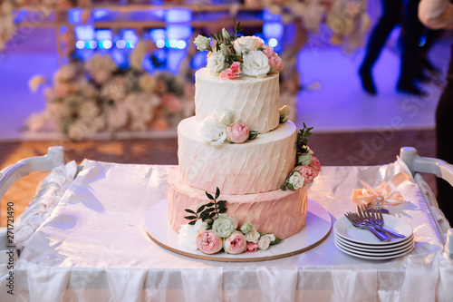 Big white wedding cake with pink roses on table