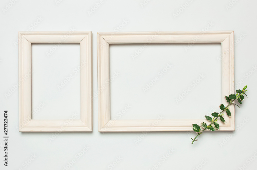White wooden photo frame and spring green twigs of plants on gray background. Flat lay top view copy space. Stylish minimal composition, artwork mockup, picture frame, home decoration White wooden photo frame and spring green twigs of plants on gray background. Flat lay top view copy space. Stylish minimal composition, artwork mockup, picture frame, home decoration