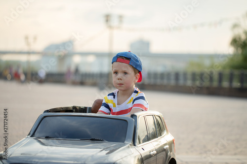 Amusement Park, a funny boy rides on a toy electric car on a sunny summer day