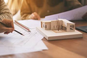 Group of an architect working and discussing about an architecture model together with shop drawing paper on table in office
