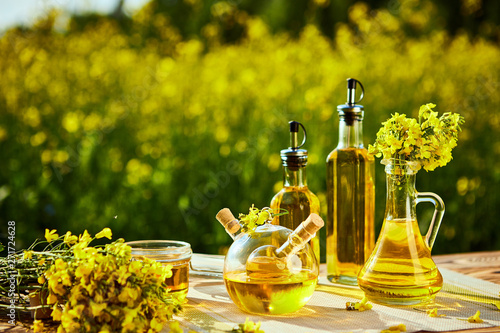 Rapeseed oil bottles (canola) on background rape field