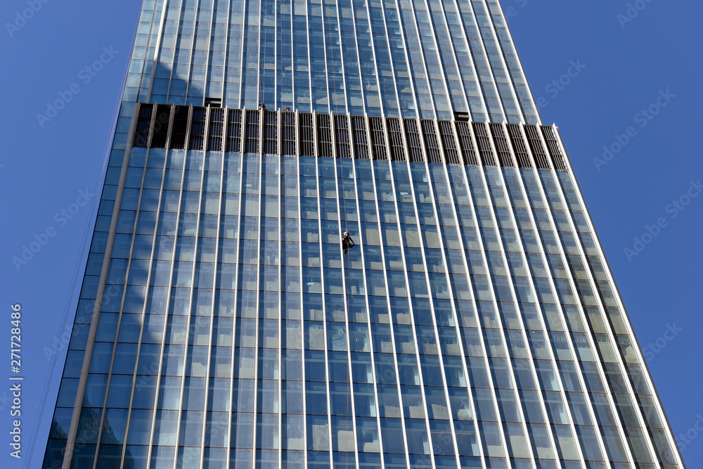 Industrial climber washes glass on the facade of a skyscraper Industrial climber washes glass on the facade of a skyscraper
