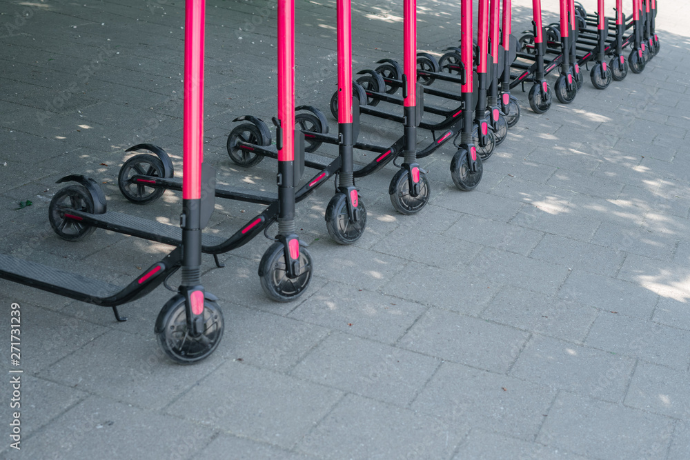 Modern eco electric city scooters for rent outdoors on the sidewalk. Alternative tourism, transportation around the city, bike replacement service. E-scooters can be rented with an app