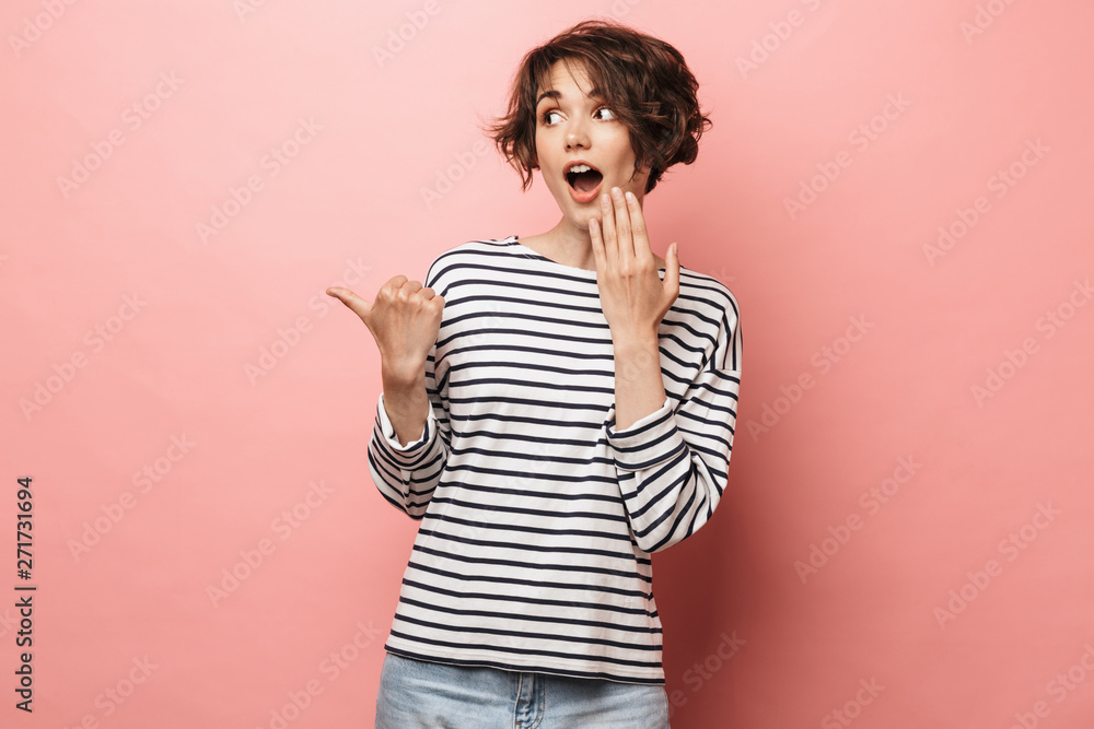 Excited shocked surprised beautiful woman posing isolated over pink wall background pointing. Excited shocked surprised beautiful woman posing isolated over pink wall background pointing.