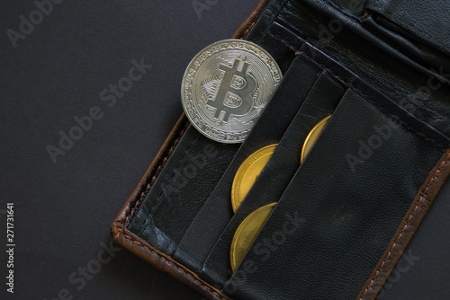 Bitcoin sticking out of a wallet o black background. Digital currency, block chain market.