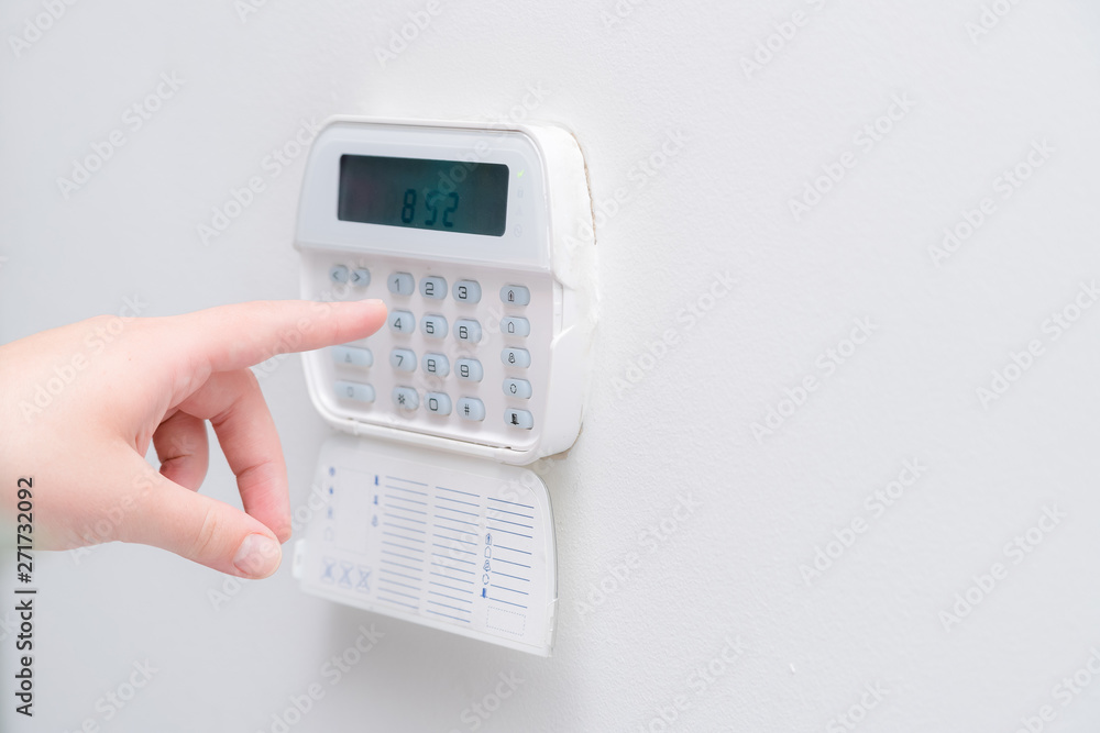 Woman hand entering alarm system password of an apartment, house of business office. Surveillance and protection console against rubbery and thief Woman hand entering alarm system password of an apartment, house of business office. Surveillance and protection console against rubbery and thief