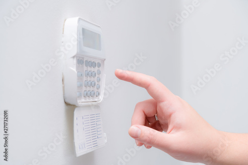 Woman hand entering alarm system password of an apartment, house of business office. Surveillance and protection console against rubbery and thief photo