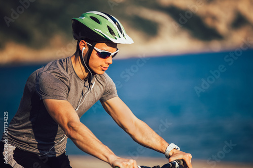 Portrait of mountain biker with helmet and sunglasses listening to music and smiling. © Mediteraneo