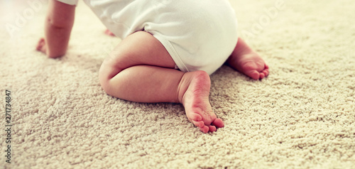 childhood, babyhood and people concept - little baby boy or girl crawling on floor at home