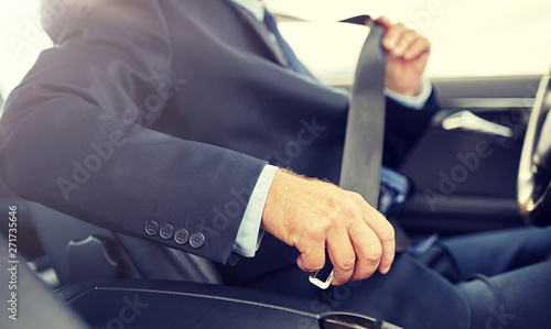 transport, business trip, safety and people concept - senior businessman fastening seat belt before driving car © Syda Productions