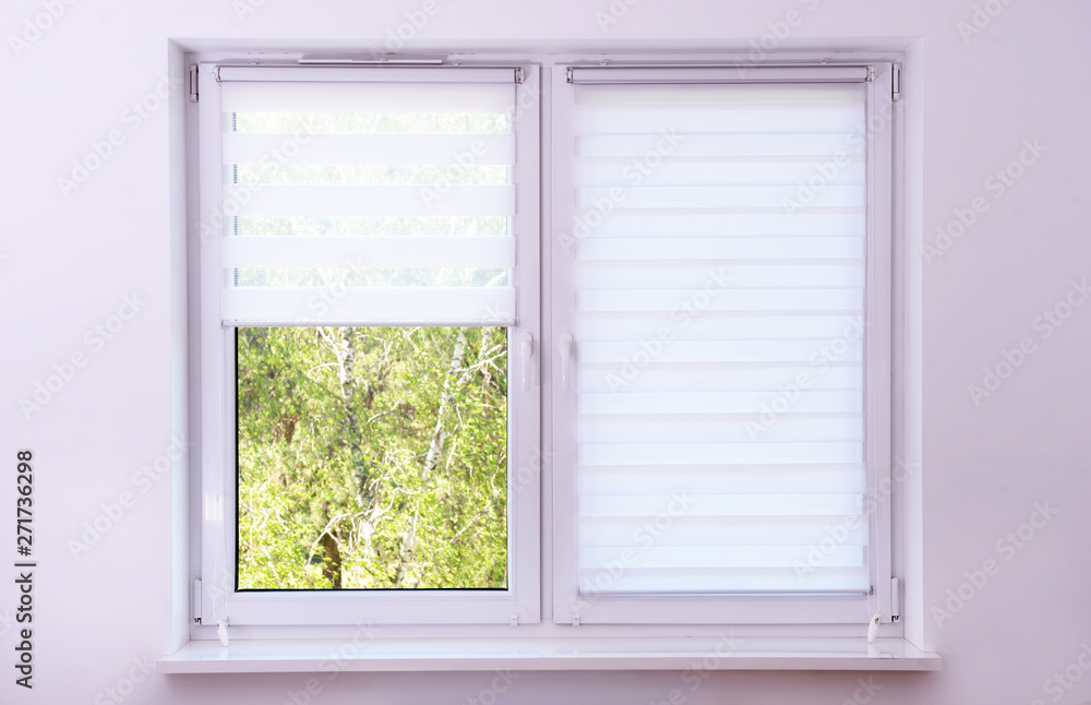 White roller blind on a metal plastic window White roller blind on a metal plastic window