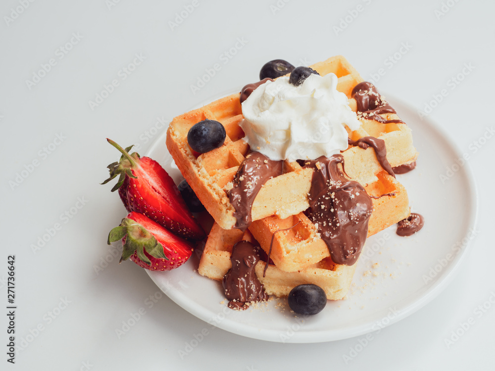 Plate with tasty breakfast. Tasty waffle with fruits, chocolate and whipped cream on a white ceramic plate Plate with tasty breakfast. Tasty waffle with fruits, chocolate and whipped cream on a white ceramic plate