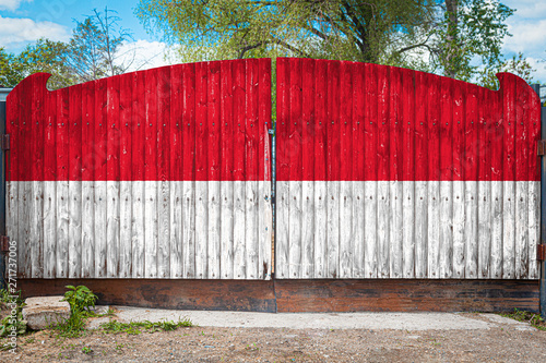 Close-up of the national flag of Indonesia on a wooden gate at the entrance to the closed territory on a summer day. The concept of storage of goods, entry to a closed area, tourism in Indonesia photo