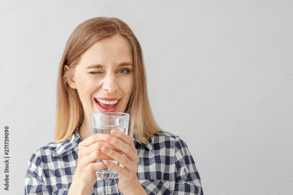 Beautiful young woman with glass of water on light background Beautiful young woman with glass of water on light background