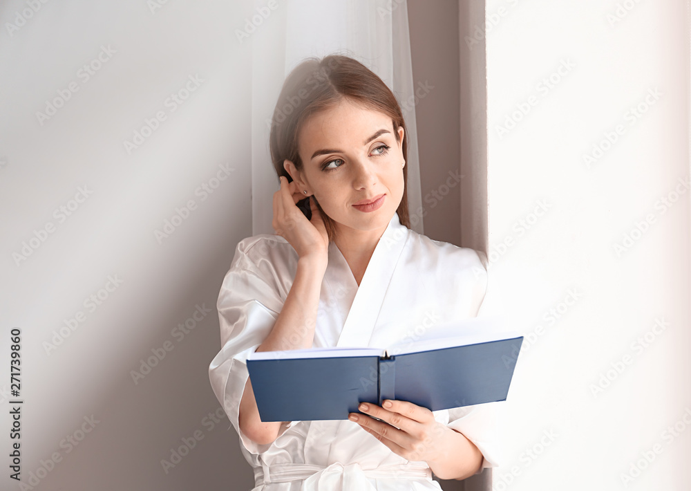 Beautiful young woman reading book near window Beautiful young woman reading book near window