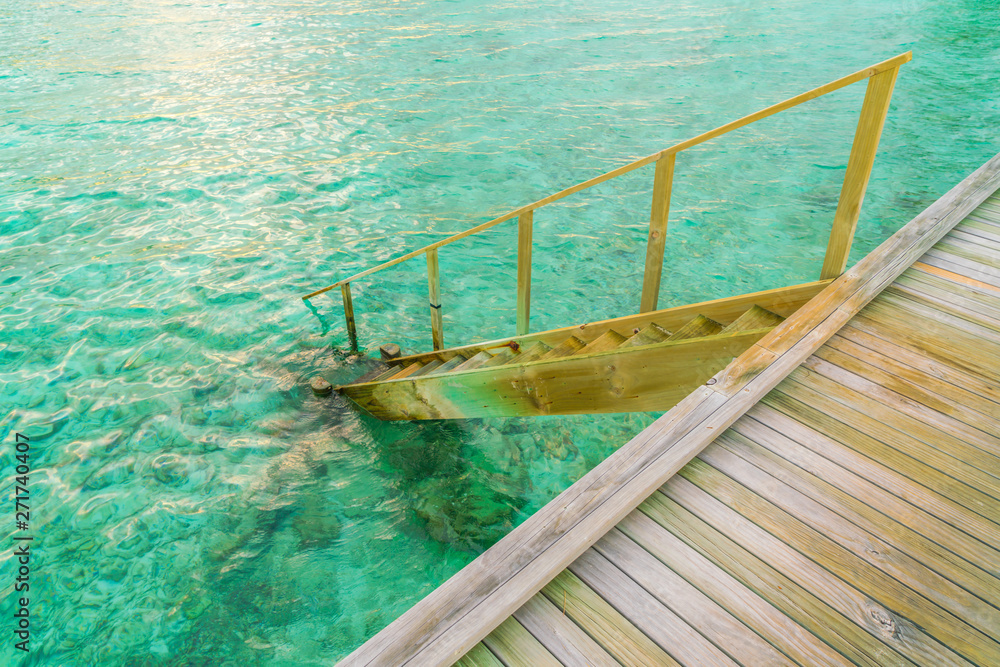 Wood stair into the sea of tropical Maldives island .
