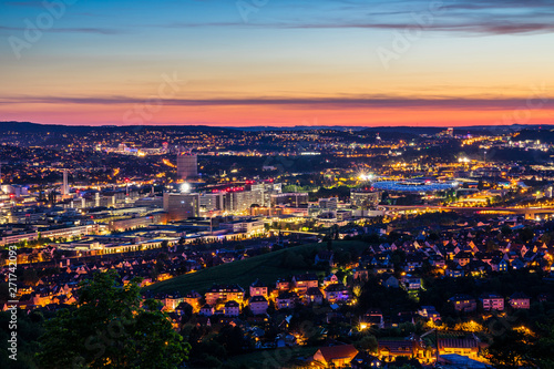Germany, Illuminated skyline of downtown stuttgart city houses and streets and arena of bad canstatt from above after sunset