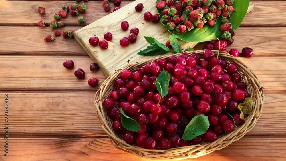 Summer harvest of cherries in a wicker basket on a wooden table Summer harvest of cherries in a wicker basket on a wooden table