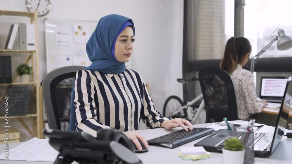Busy activity in diverse business office with asian people working multitasking in workplace networking with technology. multi ethnic chinese fashion designer with islam colleague typing on computer Busy activity in diverse business office with asian people working multitasking in workplace networking with technology. multi ethnic chinese fashion designer with islam colleague typing on computer