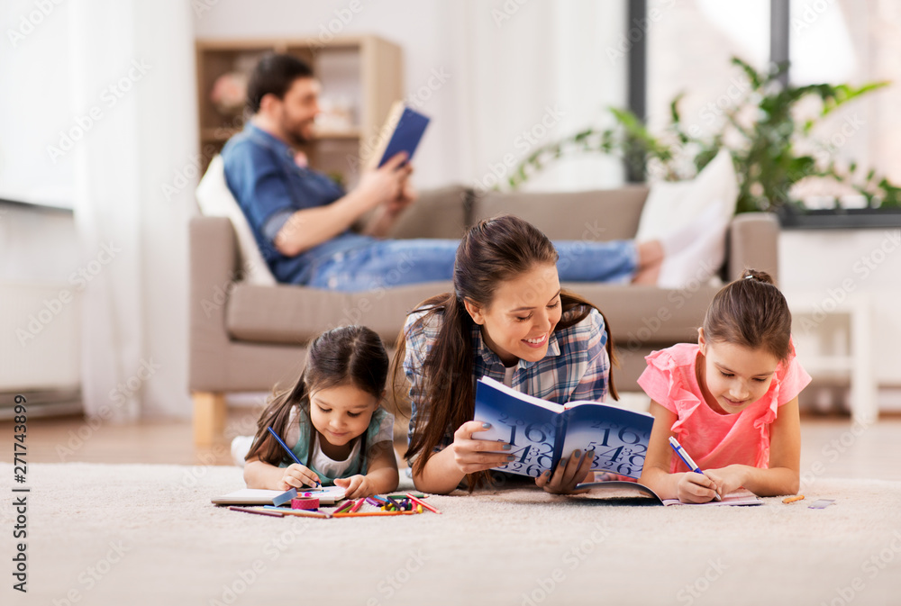 family, motherhood and leisure concept - mother spending time with her little daughters drawing in sketchbooks by crayons and lying on floor at home family, motherhood and leisure concept - mother spending time with her little daughters drawing in sketchbooks by crayons and lying on floor at home