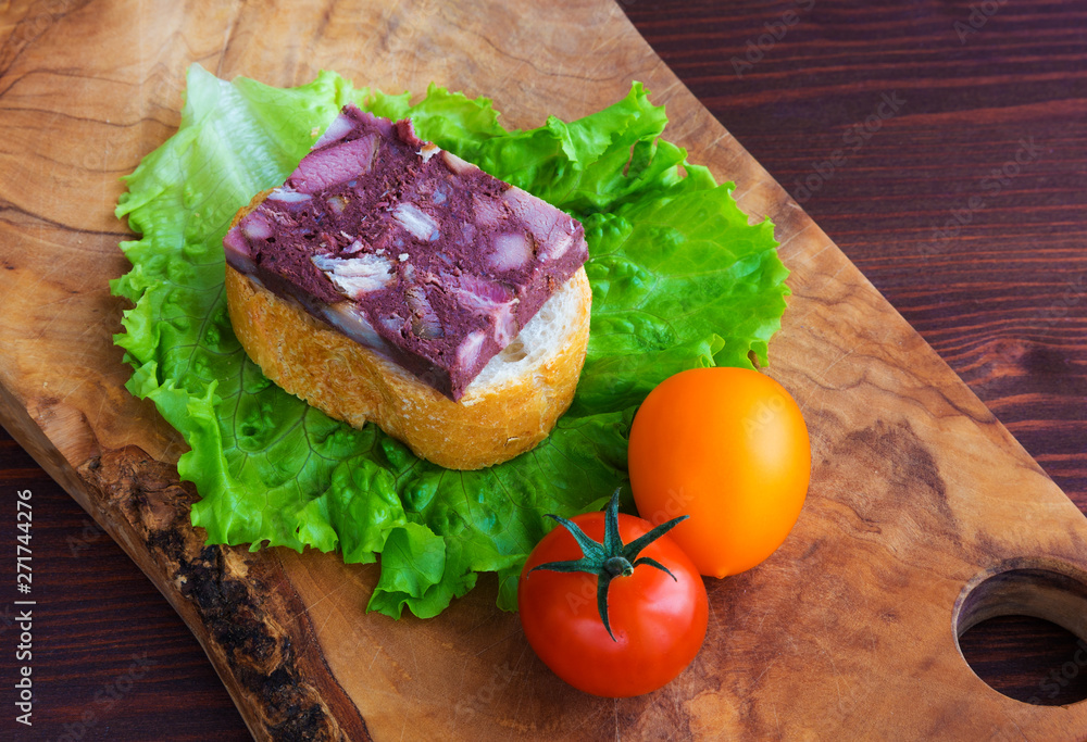 Sandwich with black pudding with a leaf of lettuce and yellow and red tomatoes are on the olive board, natural wood. Sandwich with black pudding with a leaf of lettuce and yellow and red tomatoes are on the olive board, natural wood.