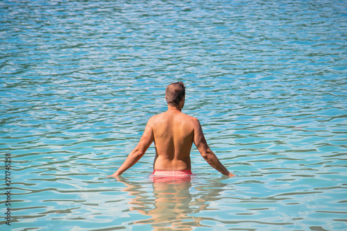 man relaxing in the water in a summer day  attractive caucasian male wearing swimsuit enjoying the sea