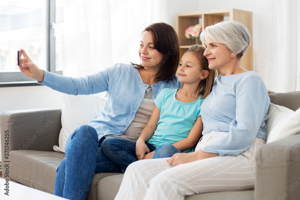 family, generation and technology concept - happy mother, daughter and grandmother taking selfie by smartphone at home family, generation and technology concept - happy mother, daughter and grandmother taking selfie by smartphone at home