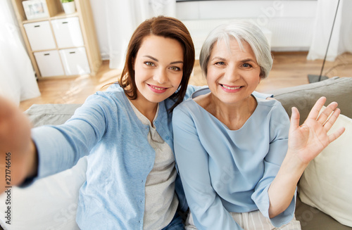 family, generation and people concept - portrait of senior mother and adult daughter taking selfie at home © Syda Productions