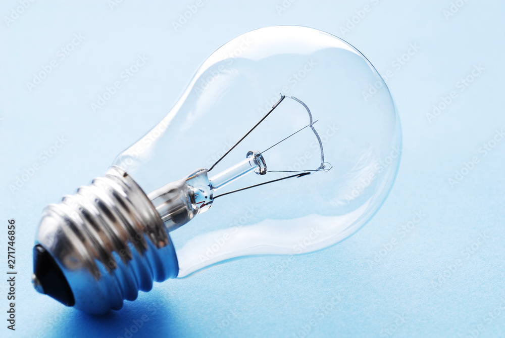 Traditional light bulb. Transparent glass light bulb on blue background. Traditional light bulb. Transparent glass light bulb on blue background.