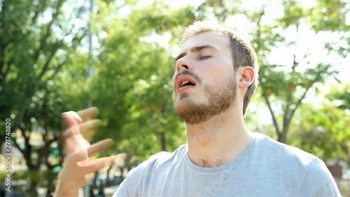 Overwhelmed man drying sweat in a hot summer day standing in a park