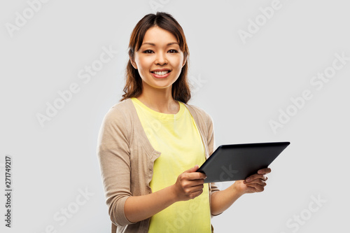 technology and people concept - happy asian woman using tablet computer over grey background