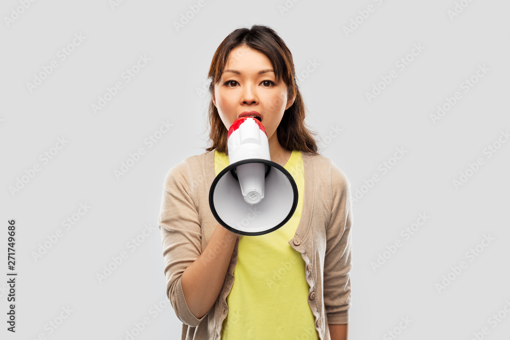 communication, feminism and human rights concept - asian young woman speaking to megaphone over grey background communication, feminism and human rights concept - asian young woman speaking to megaphone over grey background