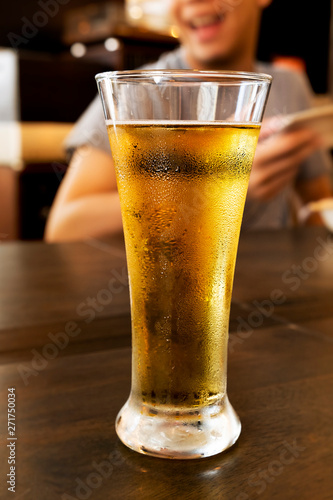 Cold beer in a tall glass on a wooden table