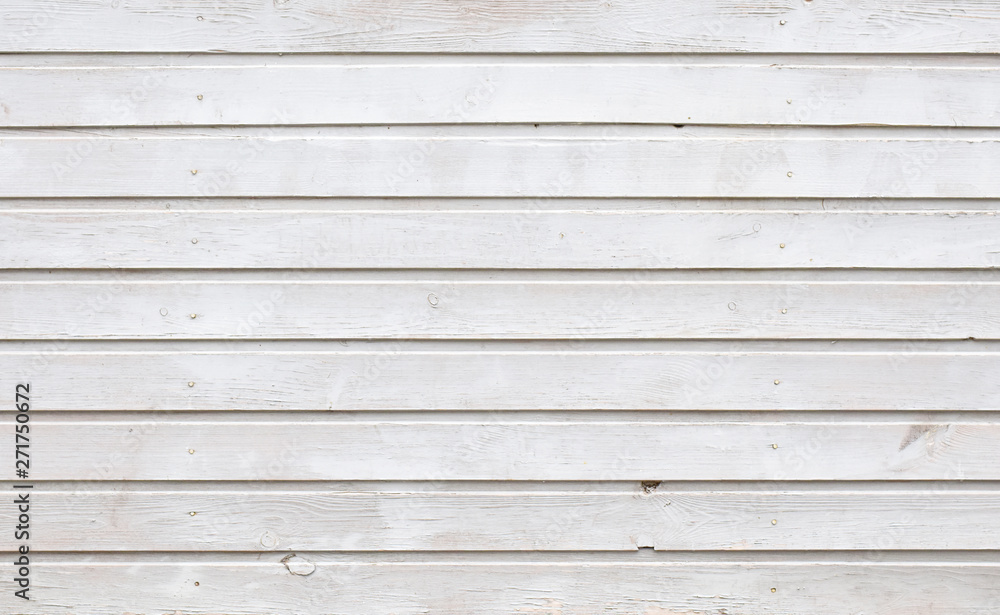 The unique texture of painted white oil paint wooden planks of the old building with ranks rows of hammered nails