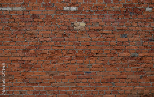 The unique texture of the old, partially destroyed brick terracotta wall of the house
