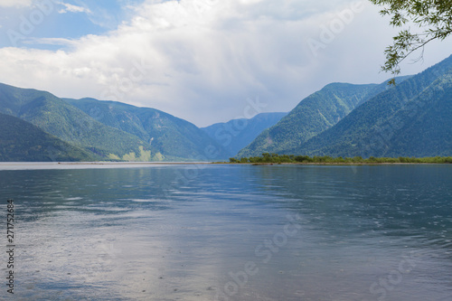 The shore of Lake Teletskoye in Altai mountains. Beautiful summer landscape. Rain drops on water.