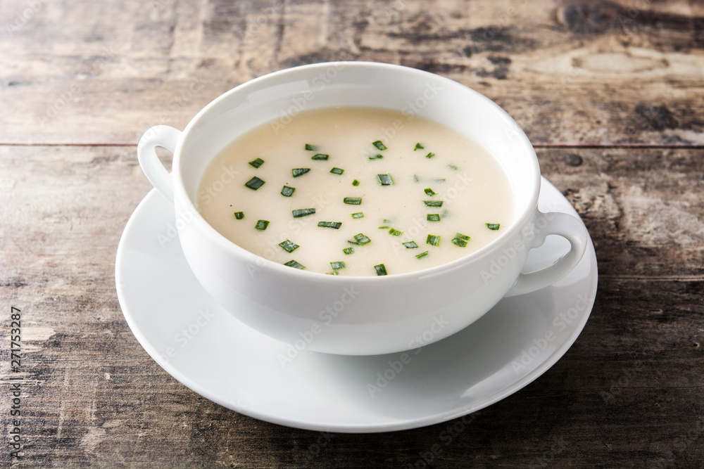 French vichyssoise soup in bowl on wooden table French vichyssoise soup in bowl on wooden table