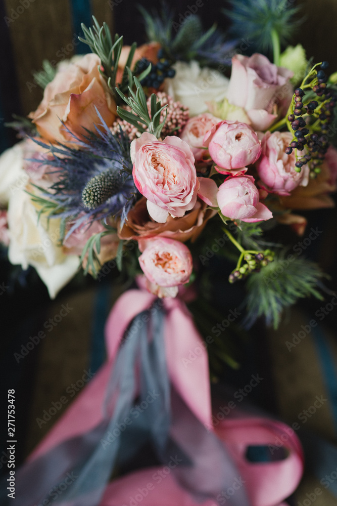 Beautiful modern bridal bouquet of colorful fresh flowers with sikl ribbons. Classic wedding traditional accessory.
