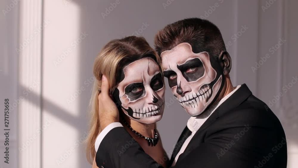 Portrait of a young couple in the Halloween mask. Close-up view of couple of painted halloween holy chracters woman and man. Loving young couple with sugar skull make-up. Portrait of a young couple in the Halloween mask. Close-up view of couple of painted halloween holy chracters woman and man. Loving young couple with sugar skull make-up.