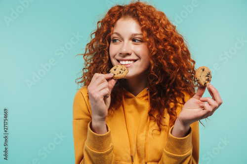 Foto Portrait of alluring redhead woman 20s smiling and eating sweet cookies