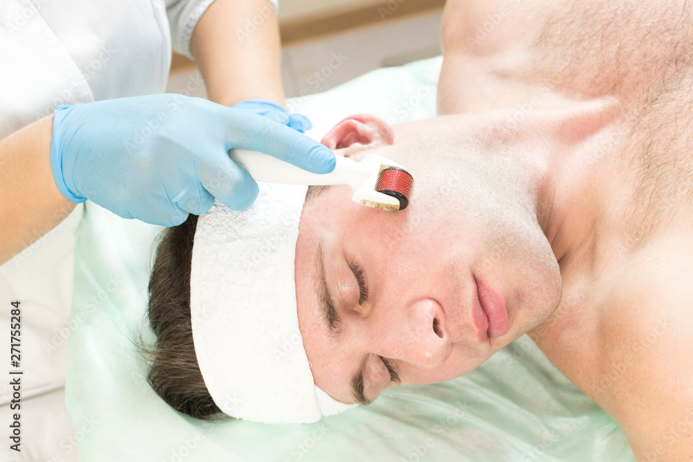Young man on the procedure of rejuvenation and cleansing of the skin of the modern medical instrument derma roller. Young man on the procedure of rejuvenation and cleansing of the skin of the modern medical instrument derma roller.