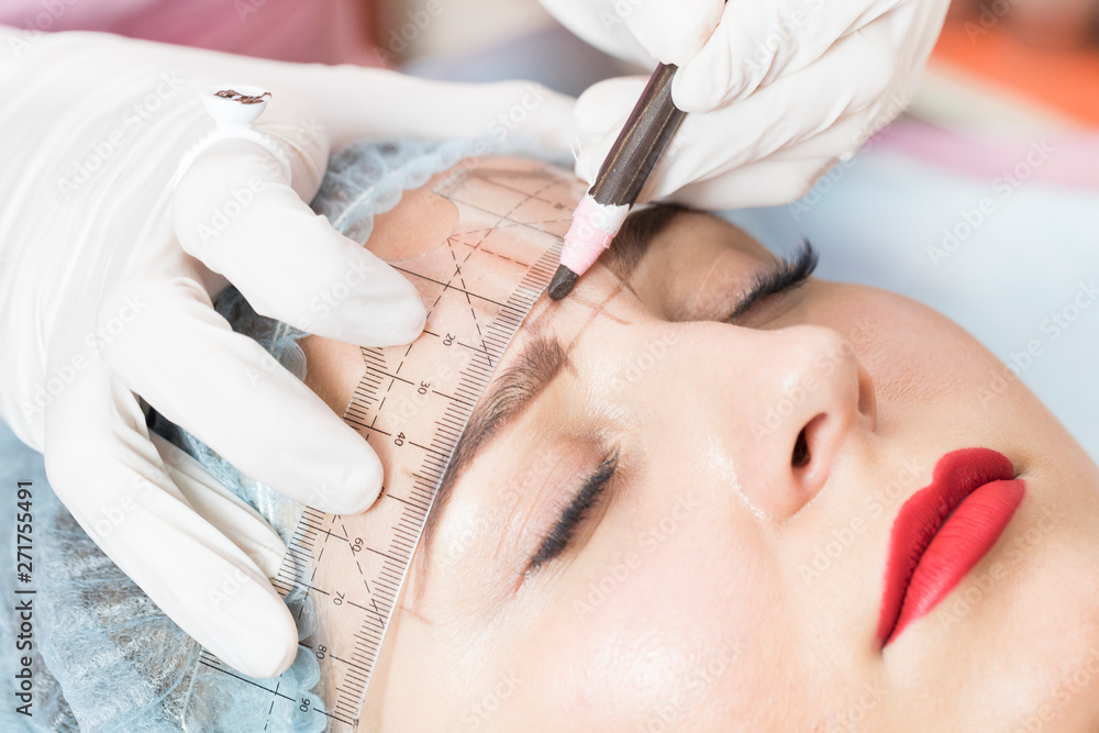Naklejka premium A young girl is carried out the correction of eyelashes in the beauty salon close-up. 
